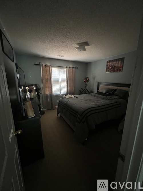 A bedroom with a bed, dresser, and window.
