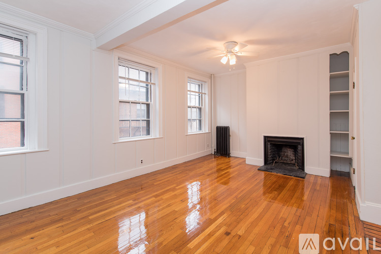 A large empty room with wood floors and a fireplace.