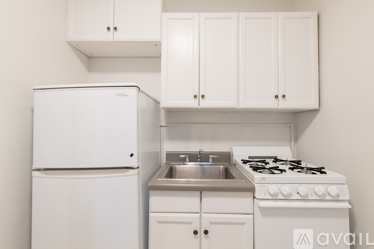 A white kitchen with a fridge, stove, and cabinets.