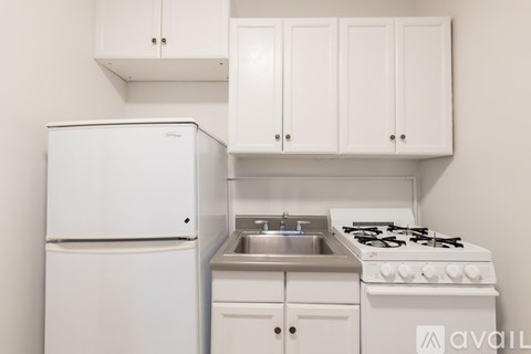 A white kitchen with a fridge, stove, and cabinets.