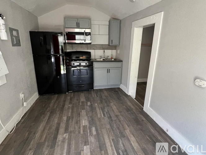 A kitchen with black appliances and wooden floors.