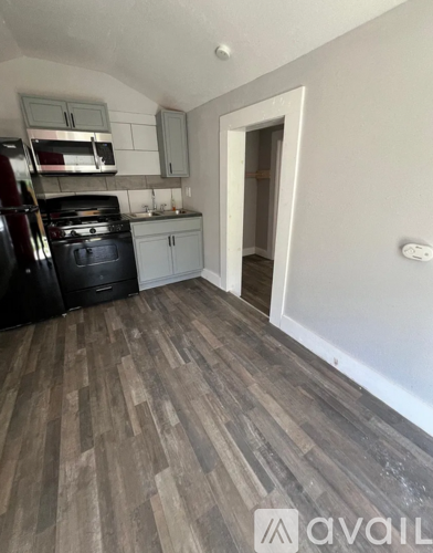 A kitchen with a black stove top oven and a black trash can.