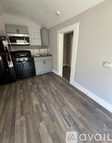 A kitchen with a black stove top oven and a black trash can.