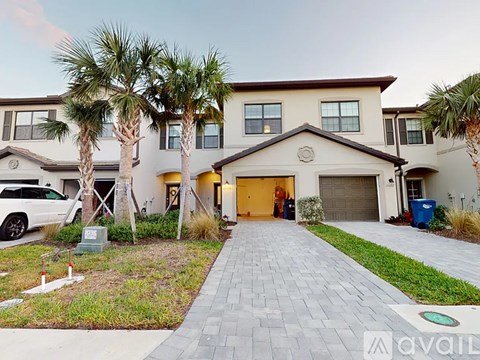 A house with a driveway and palm trees in front.