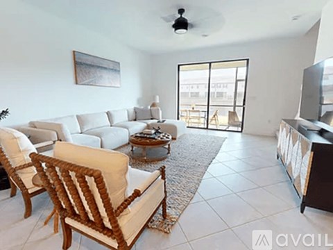 A living room with a white couch and a wooden chair.