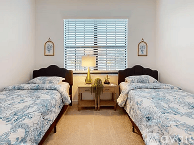 A bedroom with two beds and a nightstand with a lamp.