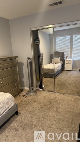 A bedroom with a bed, dresser, and a wall-mounted heater.