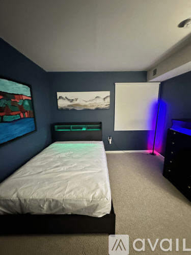 A bedroom with a bed, dresser, and a painting on the wall.