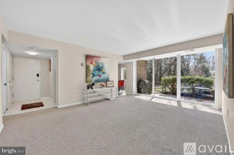 A bright living room with a carpeted floor and a large window.
