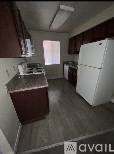 A kitchen with a white refrigerator and brown cabinets.