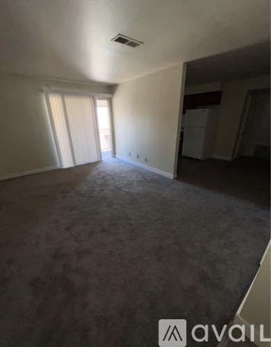 A room with a carpeted floor and a window with blinds.