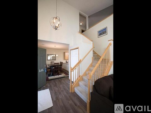 A living room with a couch, a dining table with chairs, and a staircase.
