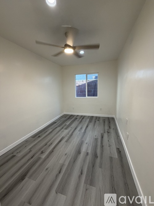 A room with a ceiling fan and a window showing a building outside.