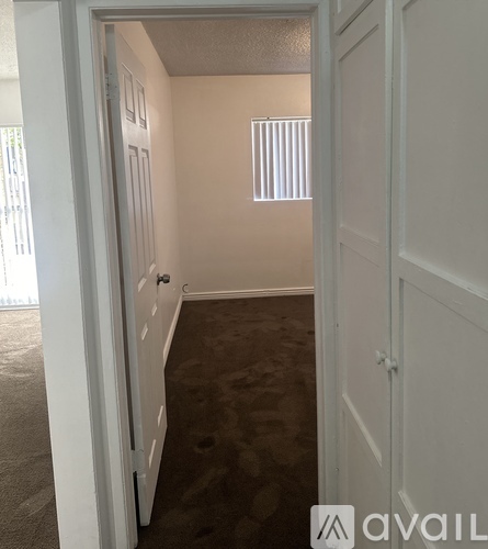 A hallway with carpeted flooring and white walls.
