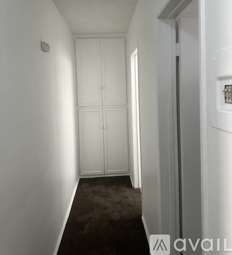 A hallway with a carpeted floor and white walls.