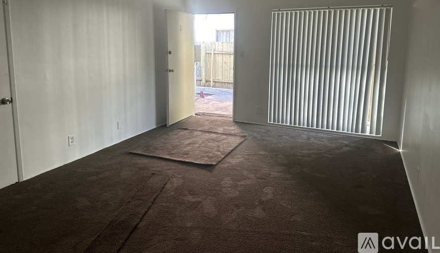A room with a brown carpet and white walls.