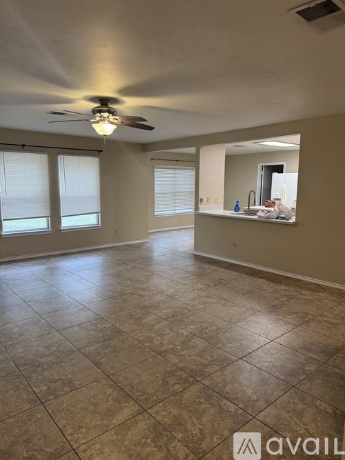 A spacious room with a ceiling fan and tiled flooring.
