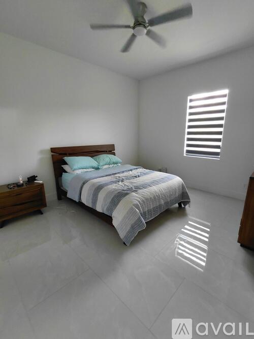 A bedroom with a bed, nightstand, and window with blinds.