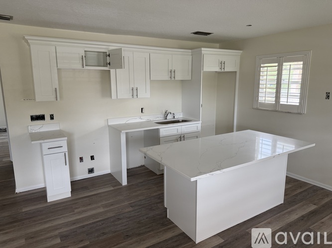 A kitchen with white cabinets and a marble countertop.
