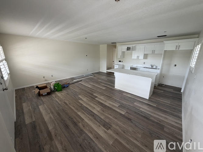 A room with wooden flooring and white walls is shown.