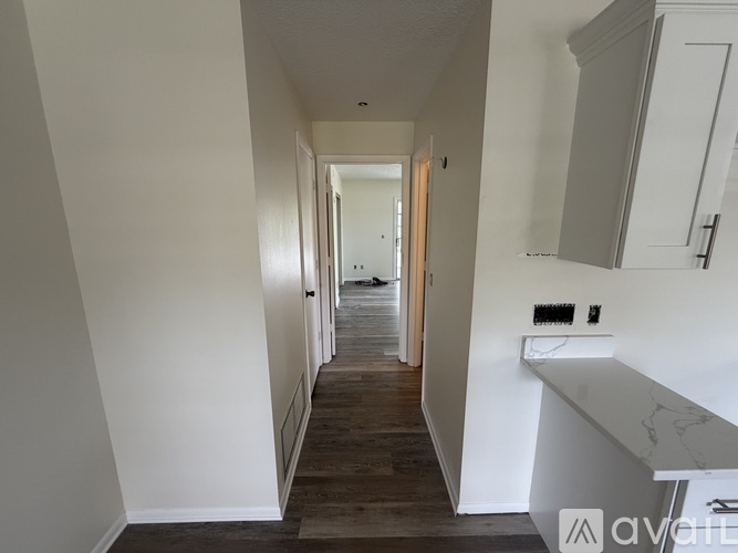 A long hallway with a white wall and a wooden floor.