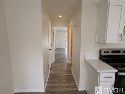 A long hallway with a white wall and a wooden floor.