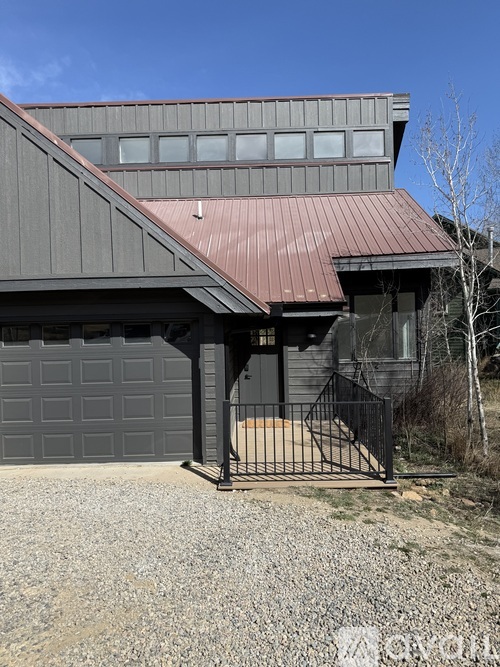 A modern house with a grey exterior and a red metal roof.