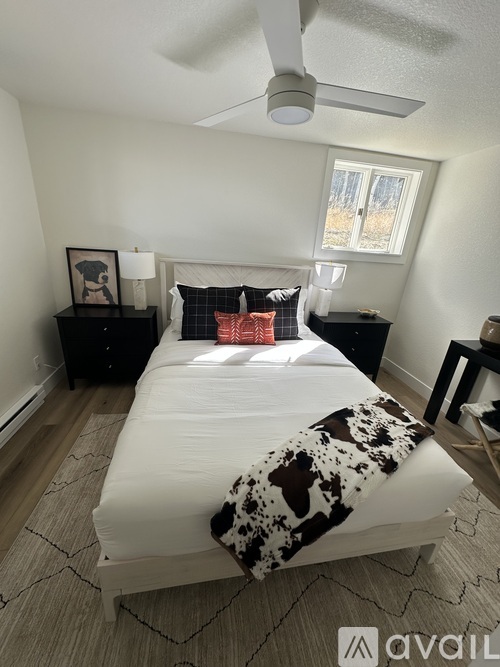 A bedroom with a bed, pillows, and a ceiling fan.