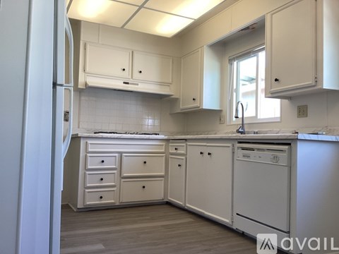 A white kitchen with a refrigerator on the left and a dishwasher on the right.