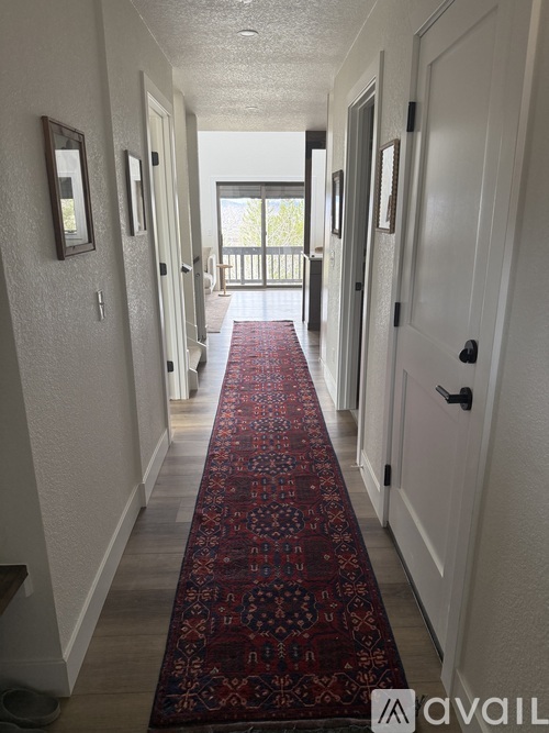 A hallway with a red carpet and white walls.