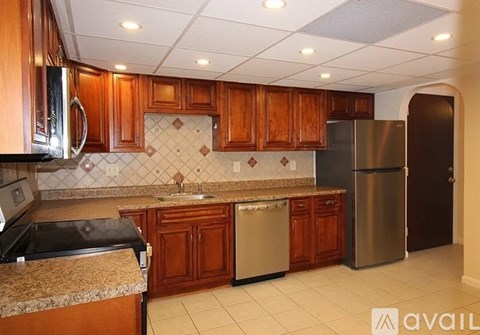 A kitchen with brown cabinets and a stainless steel refrigerator.