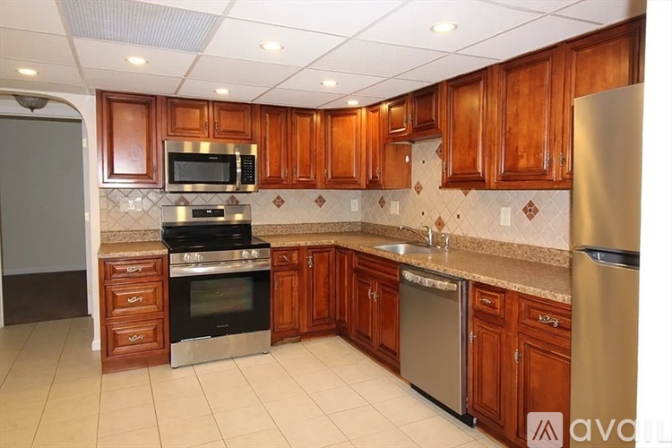 A kitchen with wooden cabinets and a stainless steel refrigerator.