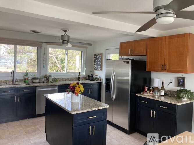 A kitchen with a refrigerator, sink, and a fan.