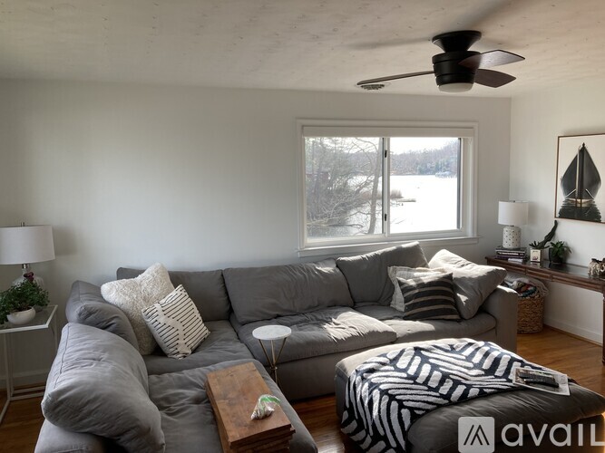 A living room with a grey couch and a ceiling fan.