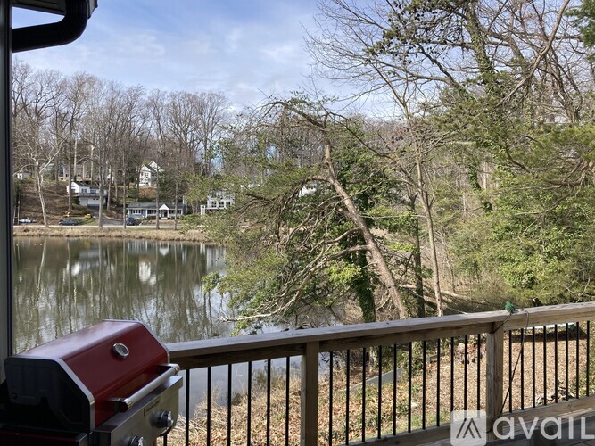 A BBQ grill is on a deck overlooking a lake.