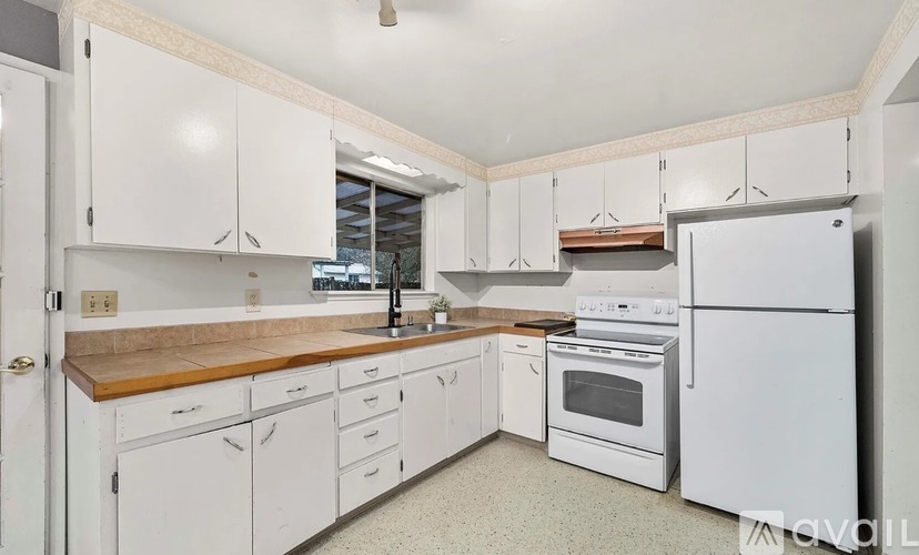 A kitchen with white cabinets and appliances.