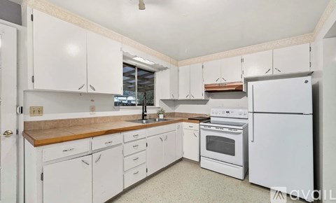 A kitchen with white cabinets and appliances.