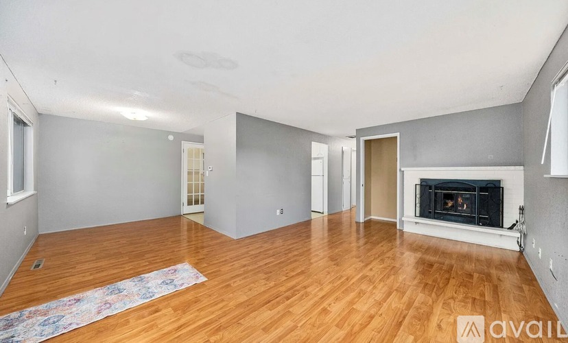 A spacious living room with a fireplace and hardwood floors.