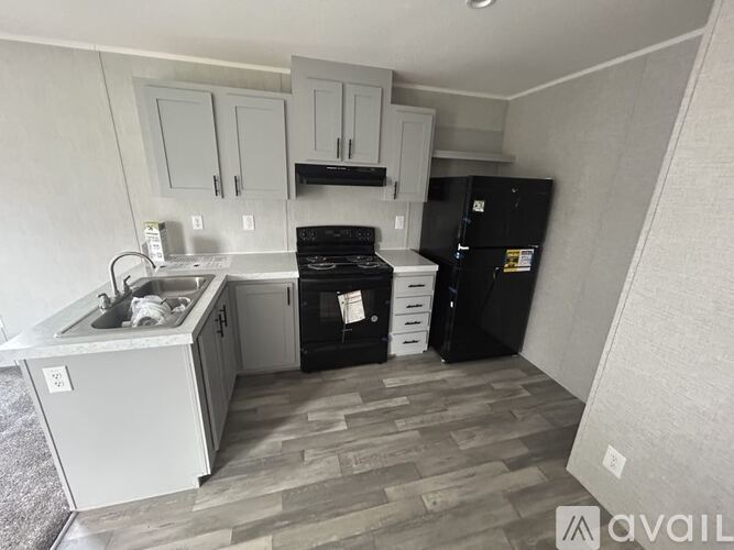 A kitchen with black appliances and wooden flooring.