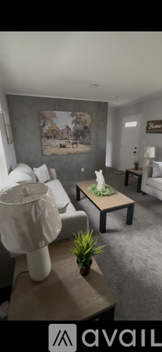 A living room with a white couch and a painting on the wall.