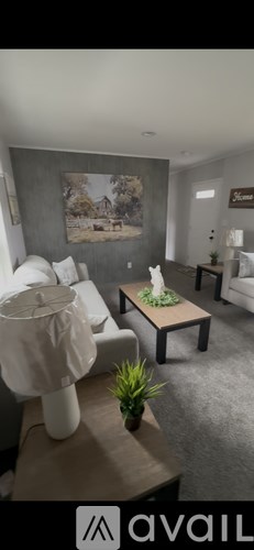 A living room with a white couch and a painting on the wall.