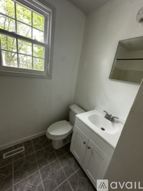A bathroom with a toilet, sink, and a window.