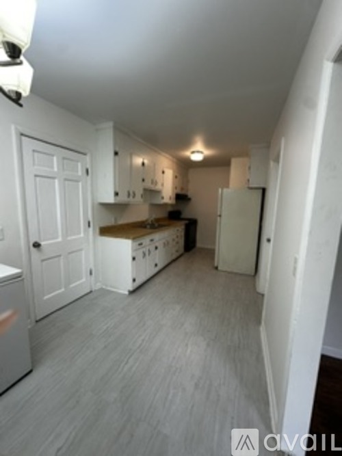 A kitchen with white cabinets and a white fridge.