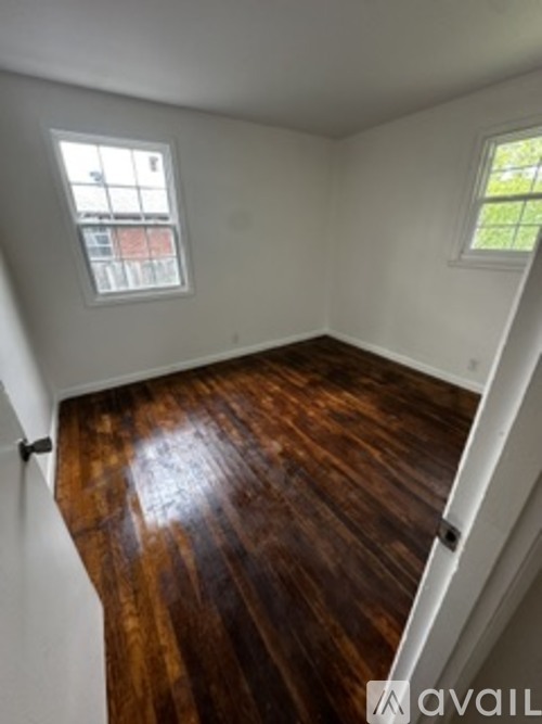 A room with wooden floors and two windows.
