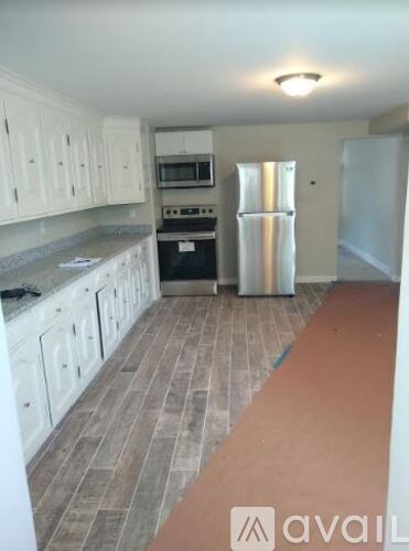 A kitchen with white cabinets and a refrigerator.