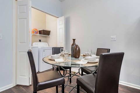 A dining room with a table set for two and a washing machine in the background.