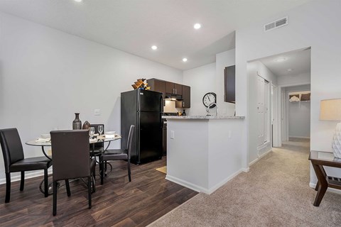 A kitchen with a black fridge and a dining table with chairs.