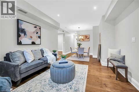 A living room with a grey couch, a blue ottoman, and a painting on the wall.