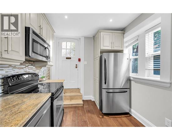 A kitchen with a stainless steel refrigerator and a stone countertop.