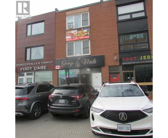 A white car is parked in front of a building with a sign that says "Savage & Nails.".
